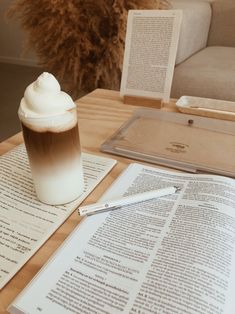 a cup of coffee sitting on top of a table next to an open book