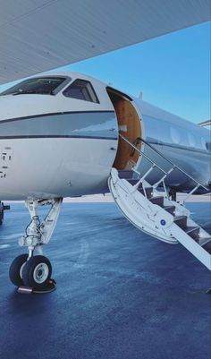 an airplane sitting on the tarmac with its door open and stairs attached to it