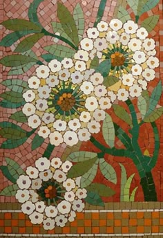 a mosaic wall with white flowers and green leaves in the center, surrounded by red tiles