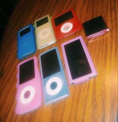 four ipods sitting on top of a wooden table next to each other, all different colors