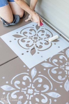 a person is painting the floor with white paint and some stencils on it