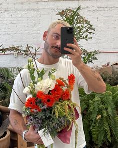 a man taking a selfie with flowers in front of him and his cell phone