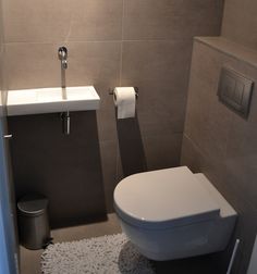 a white toilet sitting in a bathroom next to a wall mounted faucet and sink