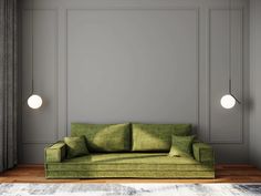 a green couch sitting on top of a wooden floor next to a wall mounted light