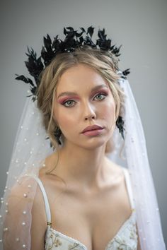 a woman wearing a veil with black flowers on her head and makeup is looking at the camera