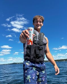 a young man standing on top of a boat holding a can