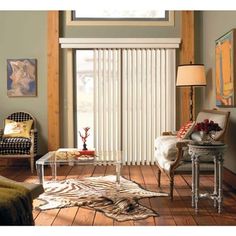 a living room with zebra rugs and chairs in front of sliding glass doors that have vertical blinds on them