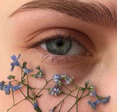 a close up of a person's eye with blue flowers