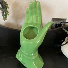 a green hand shaped vase sitting on top of a table