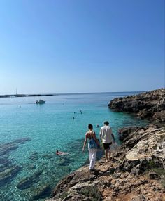 two people are walking along the shore line