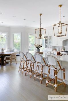 a kitchen filled with lots of white counter top space and wooden chairs next to an island