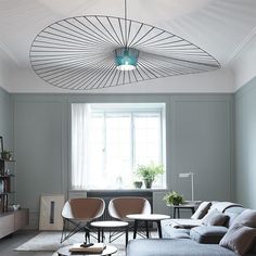 a living room filled with furniture and a round light fixture hanging over the top of it