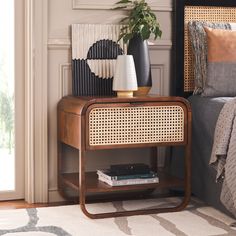 a bedroom with a bed, nightstand and plants on the side table next to it