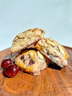 three cookies with cherries and almonds on a wooden plate next to a cherry