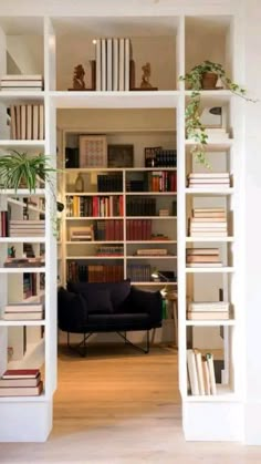 an open book shelf filled with books next to a black chair and white shelves full of books