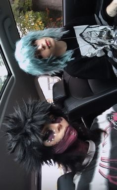 two dolls sitting in the back seat of a car with blue hair and makeup on