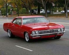 an old red car is parked on the street