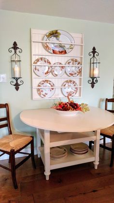 a dining room table with plates on the wall and two wooden chairs in front of it