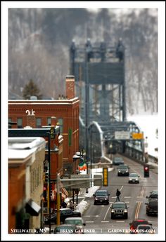 cars are driving down the road in front of a bridge