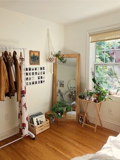 a room with a mirror, coat rack and other items on the floor in front of a window