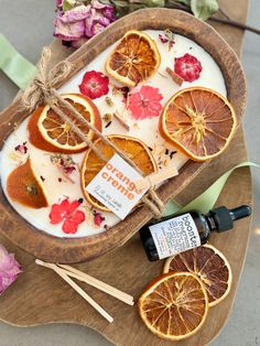 an assortment of orange slices and flowers on a tray with some essential oils next to it