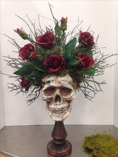 a skull with flowers in it's head on top of a table next to moss