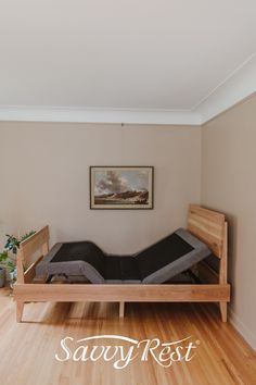 a bed sitting on top of a wooden floor next to a wall with a painting above it