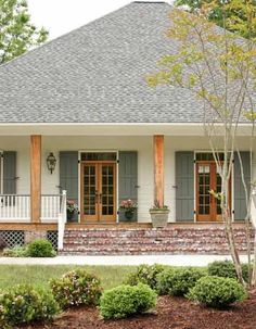 a white house with gray shutters and red brick on the front porch is shown