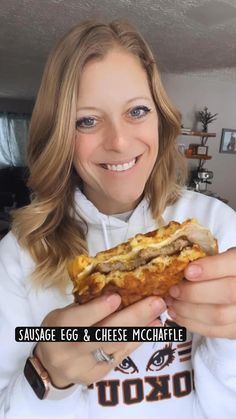 a woman holding a sandwich in her hands with the words sausage egg and cheese mchaffle on it