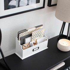 a black desk with a white container and some pictures on the wall next to it