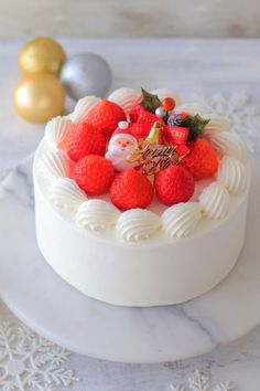 a white cake topped with strawberries sitting on top of a table next to christmas decorations