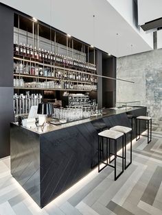 an empty bar with stools and bottles on the shelves