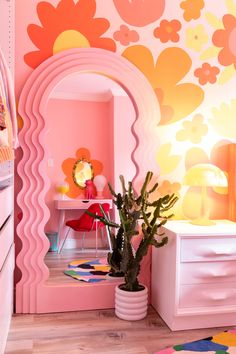 a pink room with flowers painted on the walls and a potted plant next to it