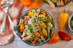 two bowls filled with pasta and vegetables on top of a table