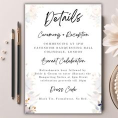 a white and blue floral wedding reception card on top of a table next to a pen