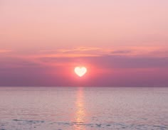 the sun is setting over the ocean with pink clouds