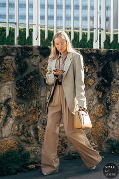 a woman is walking down the street with her purse and cell phone in her hand