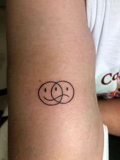 a woman's arm with a tattoo on it that has two circles in the middle