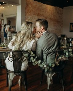 a man and woman sitting at a table with their arms around each other as they kiss