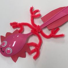 a pink toothbrush with red hair attached to it's body and eyes, sitting on top of a white surface