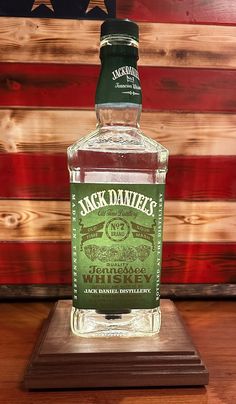 a bottle of jack daniels whiskey sitting on top of a wooden table next to an american flag