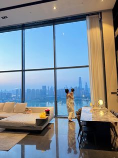 a woman standing in front of a large window looking out at the cityscape