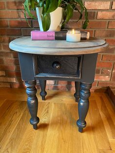 a small table with some books and a potted plant next to it on a hard wood floor