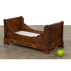 an old wooden bed with a green apple next to it