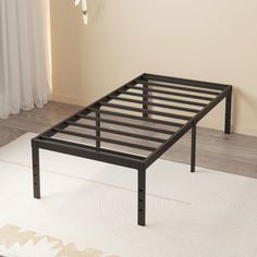 a metal bed frame sitting on top of a rug in front of a white wall