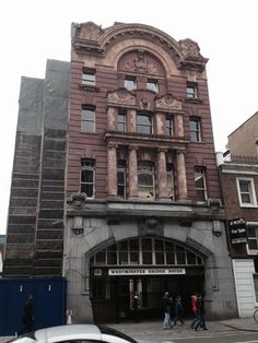 an old building on the corner of a street with cars parked in front of it