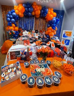 an orange table topped with lots of desserts and balloons