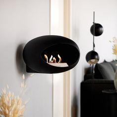 two lit candles are in the middle of a black candle holder hanging from a wall