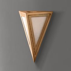 a triangular shaped light fixture mounted on a wall with a white glass shade in the corner