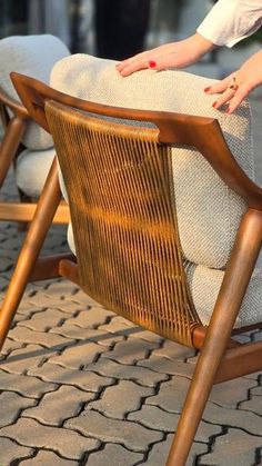 a woman sitting in a chair with her hand on the back of it's seat